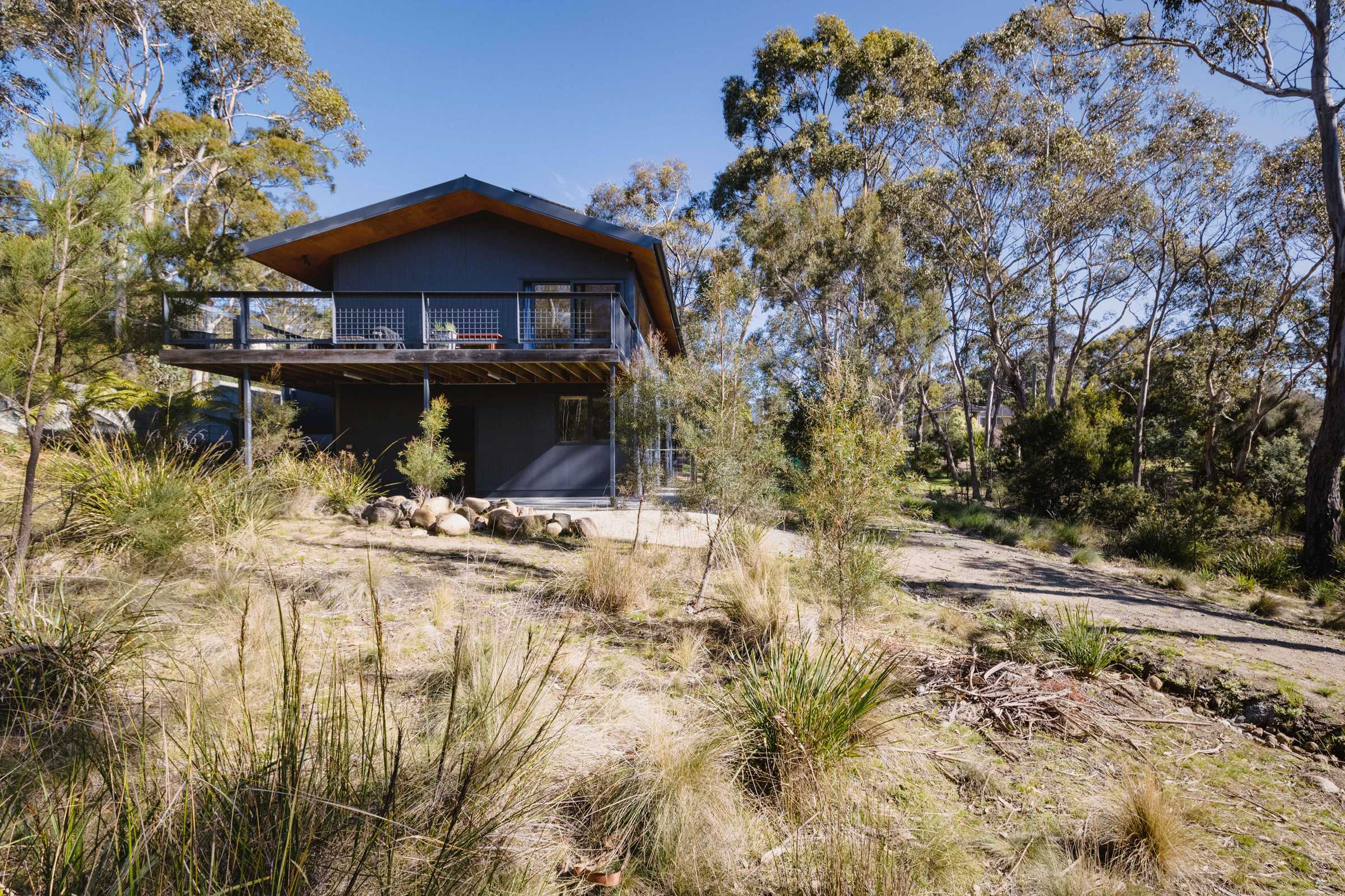 Mt Nelson home renovation to improve the amenity of the space under the house by building it in, creating two extra bedrooms and a usable under-house storage space. The house is north facing on a bush block, with mini orb cladding and exposed aggregate concrete paths to lower the fire risk. Credit: Jordan Davis.