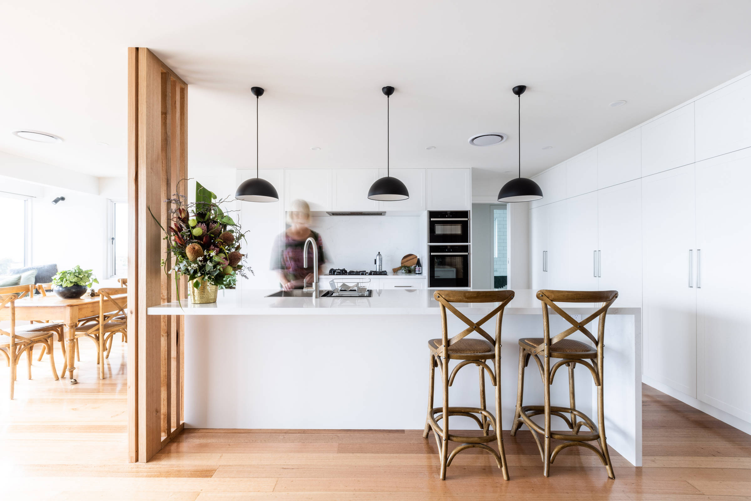 This light and bright, contemporary kitchen renovation has transformed this 1970s house and features solid stone benchtops, pendant lighting, contemporary lighting, brushed chrome tapware and an in bench sink. Credit: Jordan Davis.