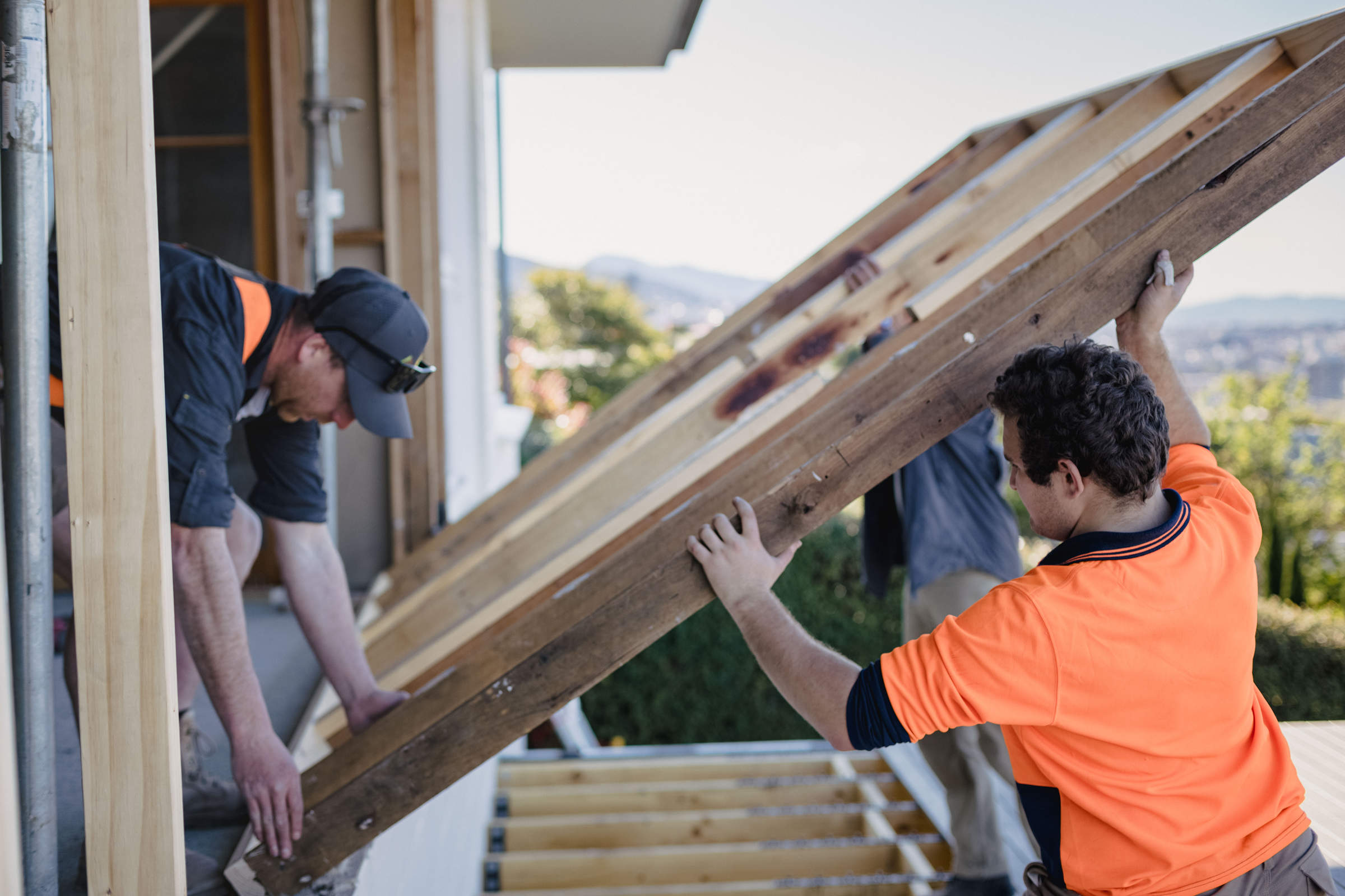 A foreman instructing a work team who are working together as a team, working on a home renovation and removing windows to finish a large front deck. The renovation is to take advantage of a water view. Credit: Jordan Davis.