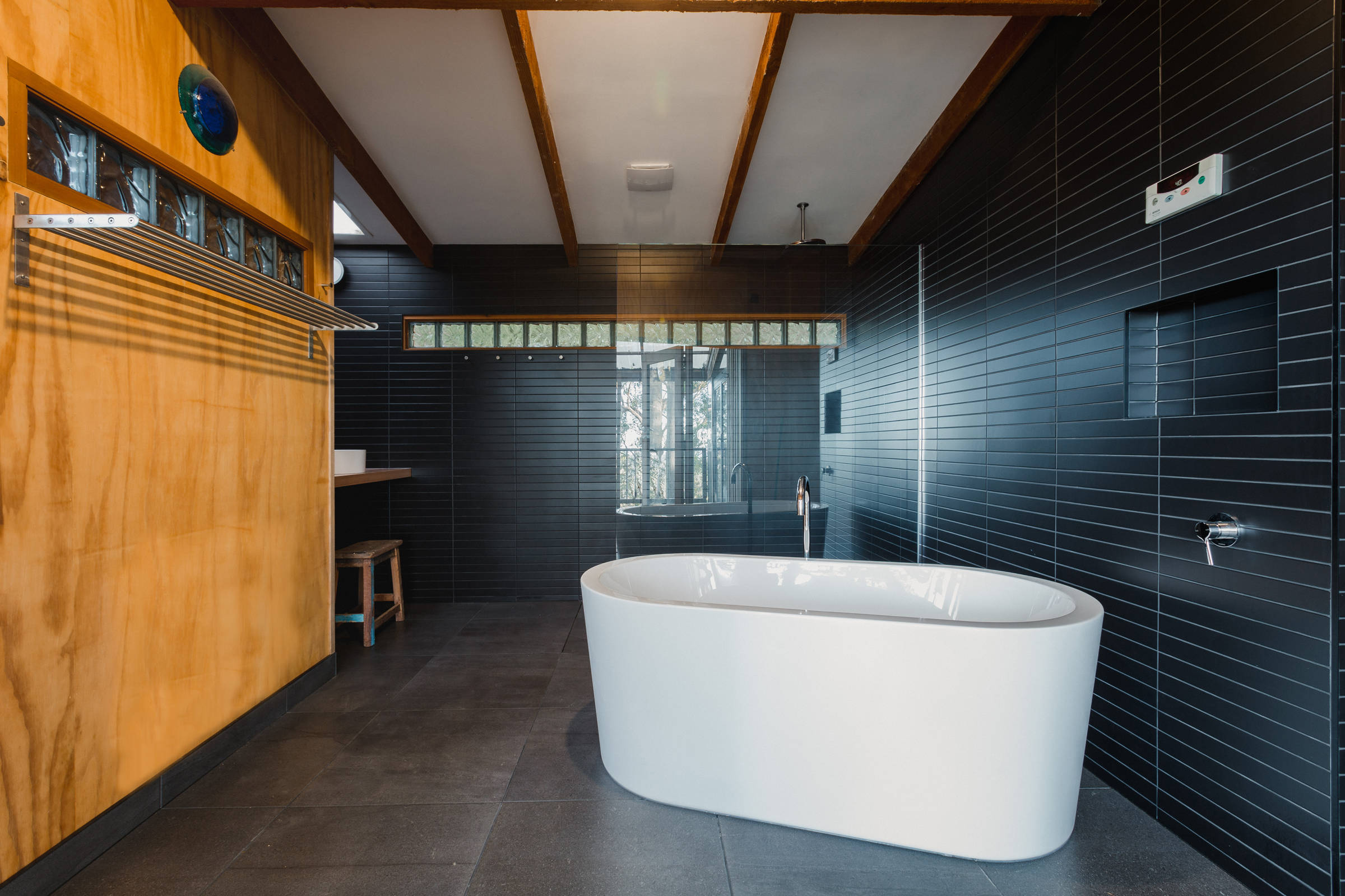 Custom Japanese inspired bathroom renovation features a freestanding bath, black mosaic tiles, laid with the utmost accuracy. This architectural bathroom renovation was designed to give a contemporary feel with increased natural light from a new skylight. Credit: Jordan Davis.