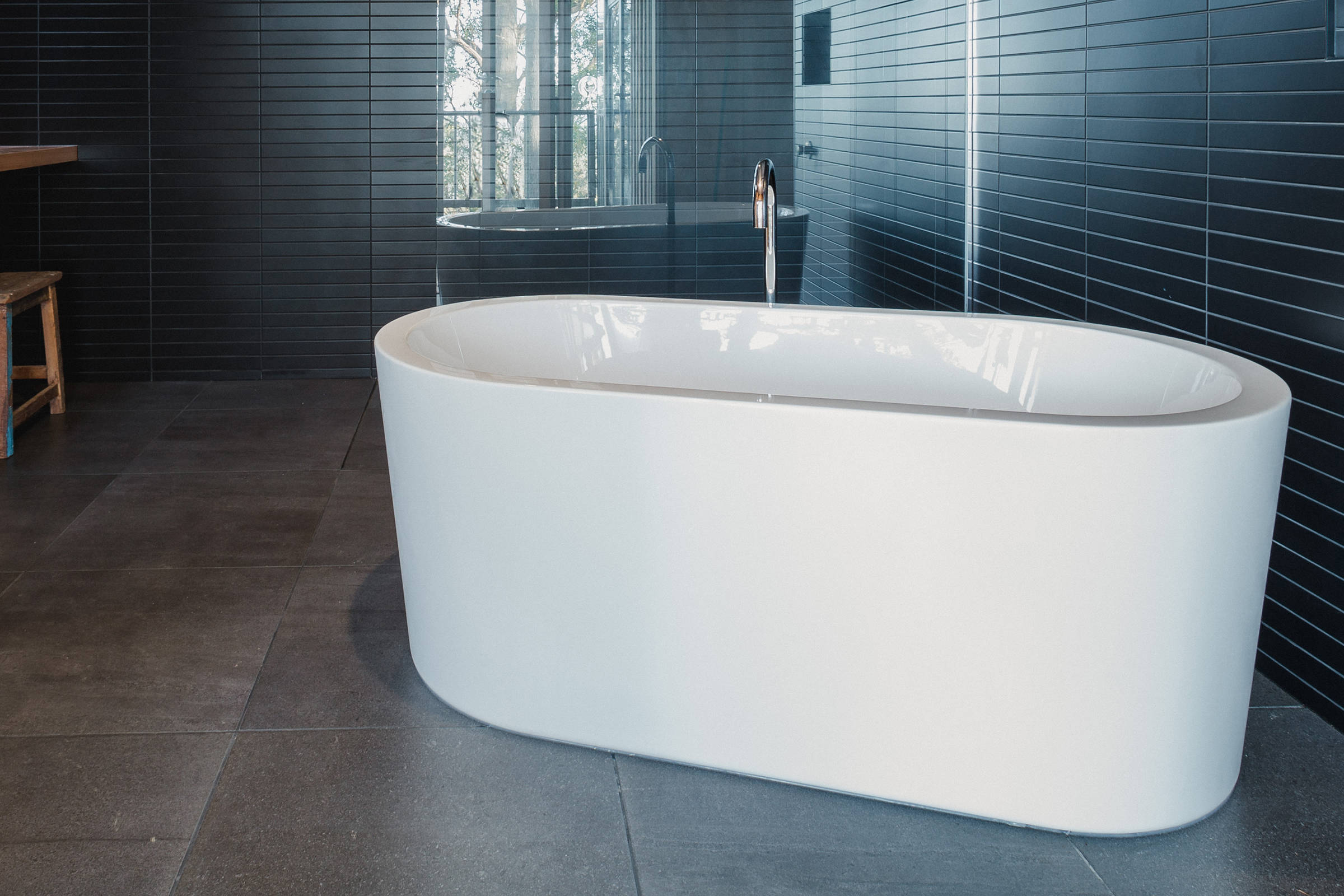 Custom Japanese inspired bathroom renovation features a freestanding bath, black mosaic tiles, laid with the utmost accuracy. This architectural bathroom renovation was designed to give a contemporary feel with increased natural light from a new skylight. Credit: Jordan Davis.