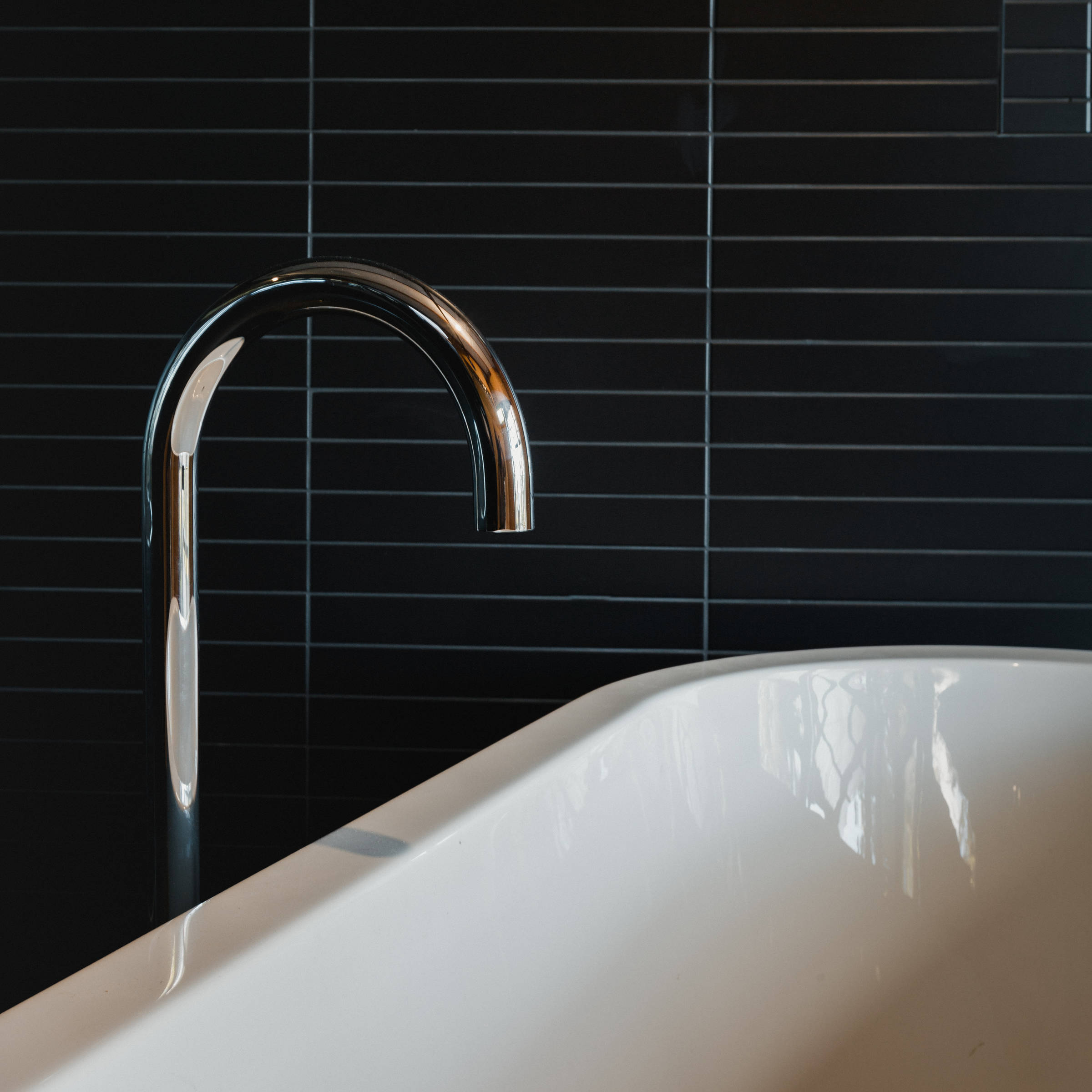 A Japanese inspired bathroom renovation with a freestanding bath, highlighted by black mosaic tiles and chrome tapware. Credit: Jordan Davis.