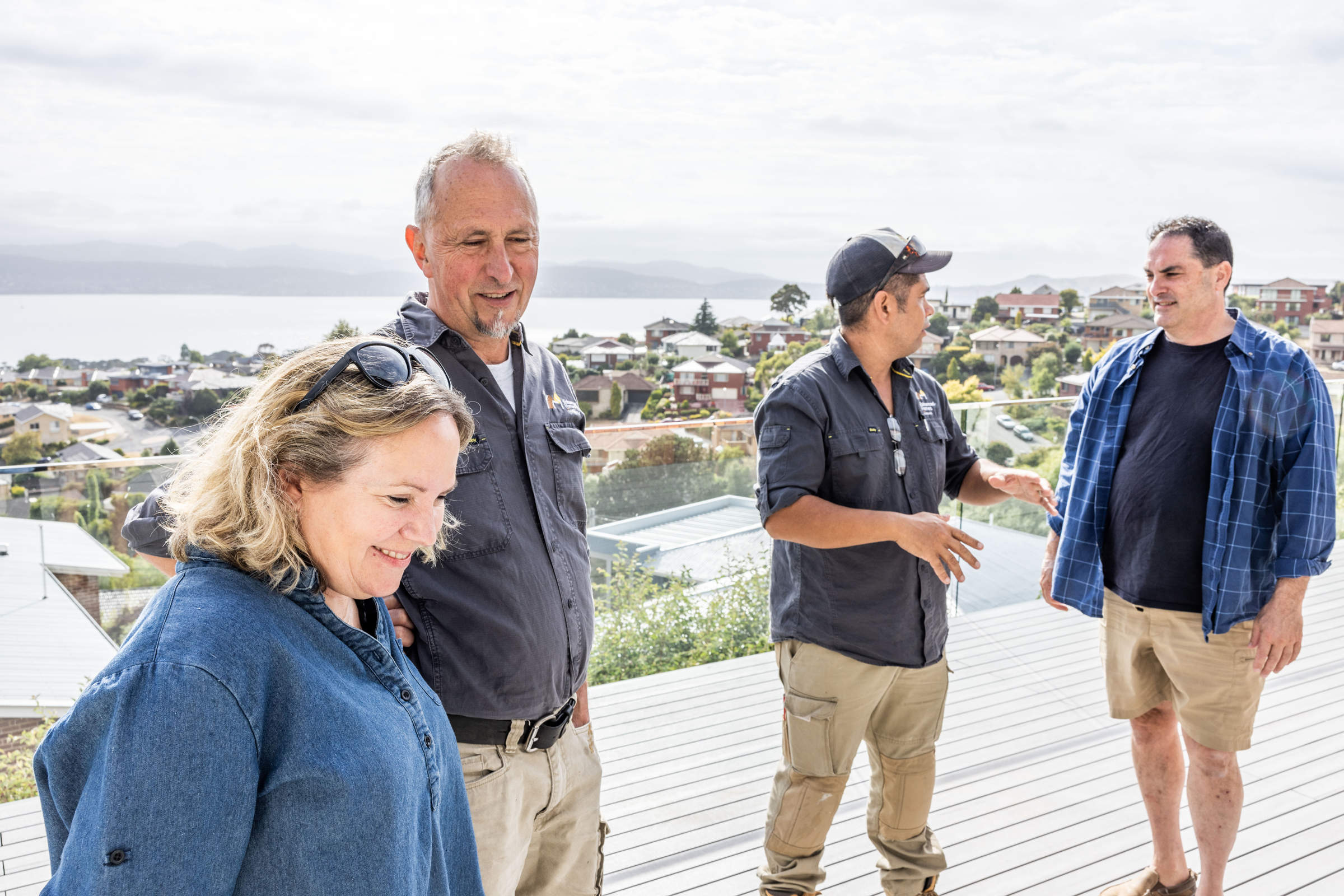 The Enhanced Homes team consulting with our clients about the renovation of their 1970s home, standing on their new deck with view of the River Derwent. Credit: Jordan Davis.