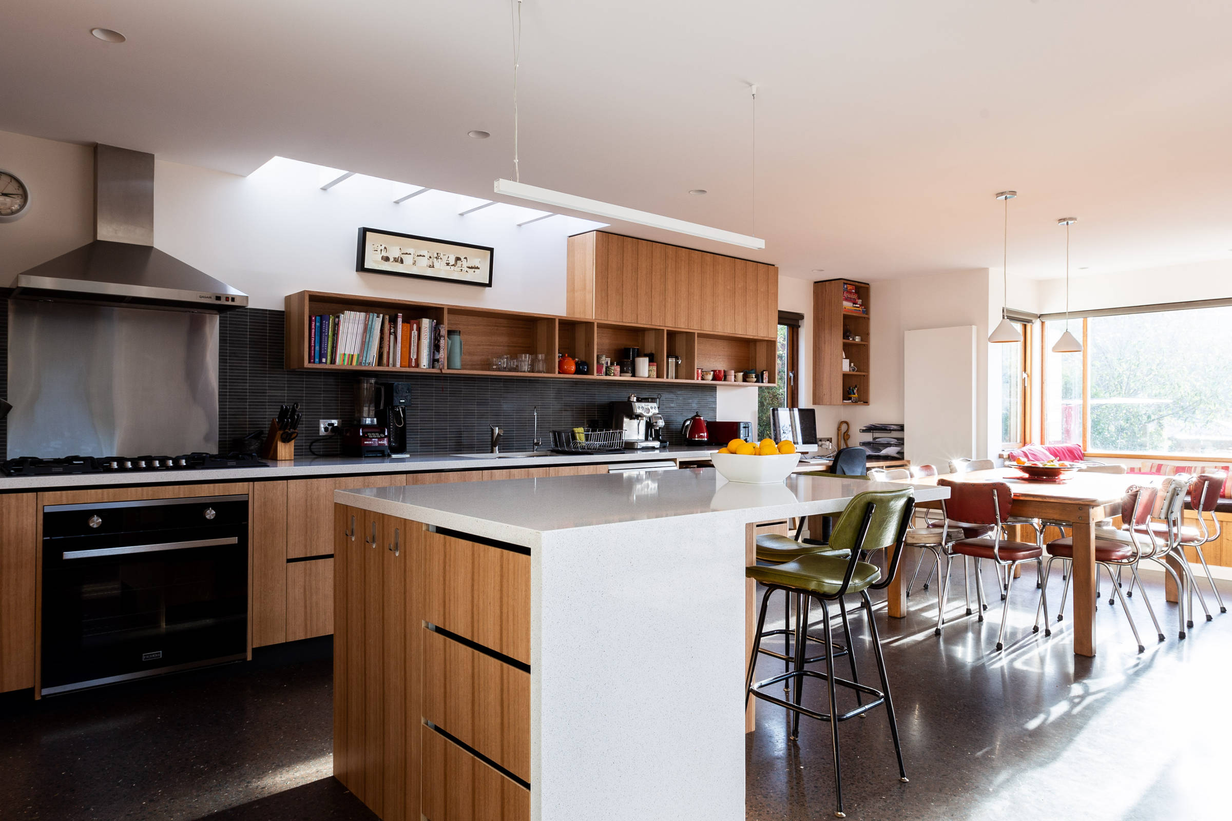 Kitchen renovation featuring solid Tasmanian oak shelving, handle-free joinery, mosaic tiled splashbacks, stone benchtops and improving natural light into the kitchen and living areas. Credit: Jordan Davis.