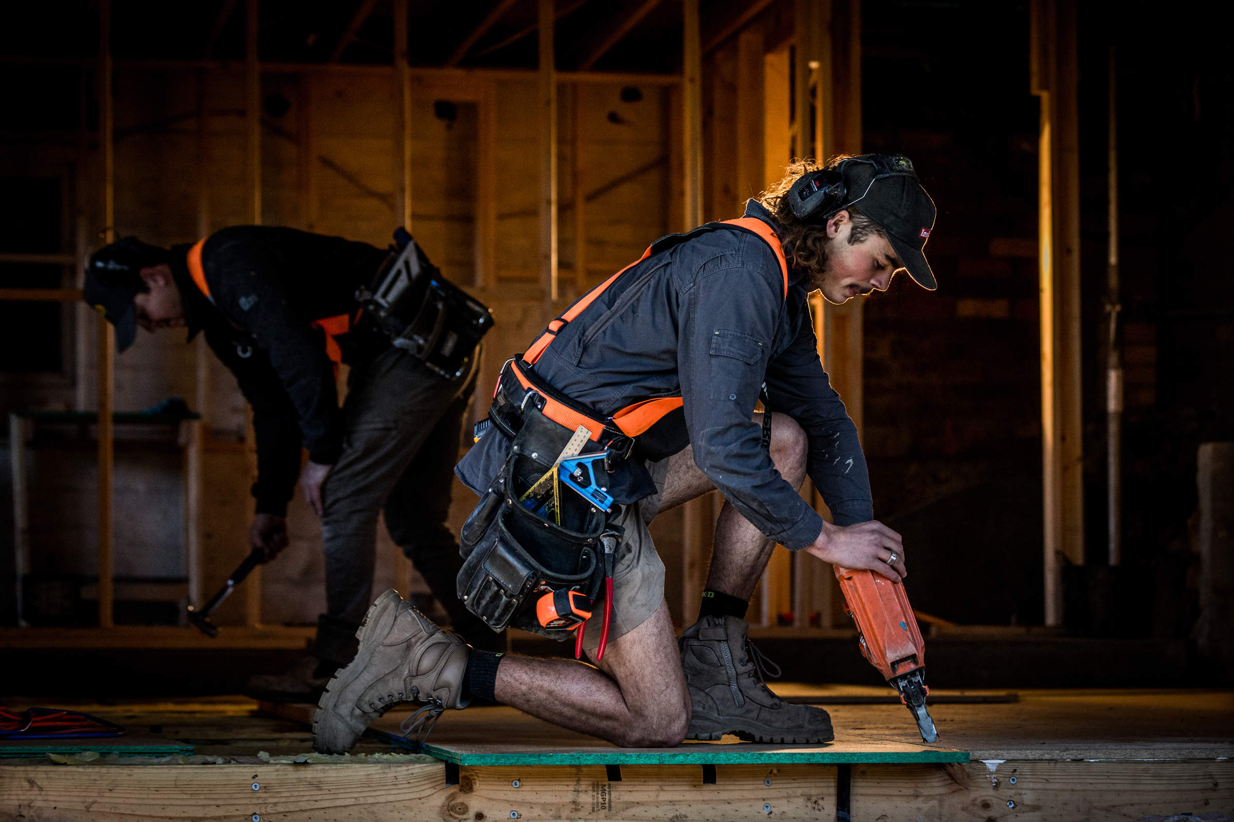 Experienced builder supporting and guiding the next generation of apprentices, teaching timber framing and nailing a floor as part of home renovation and extensions. Credit: Natalie Mendham.