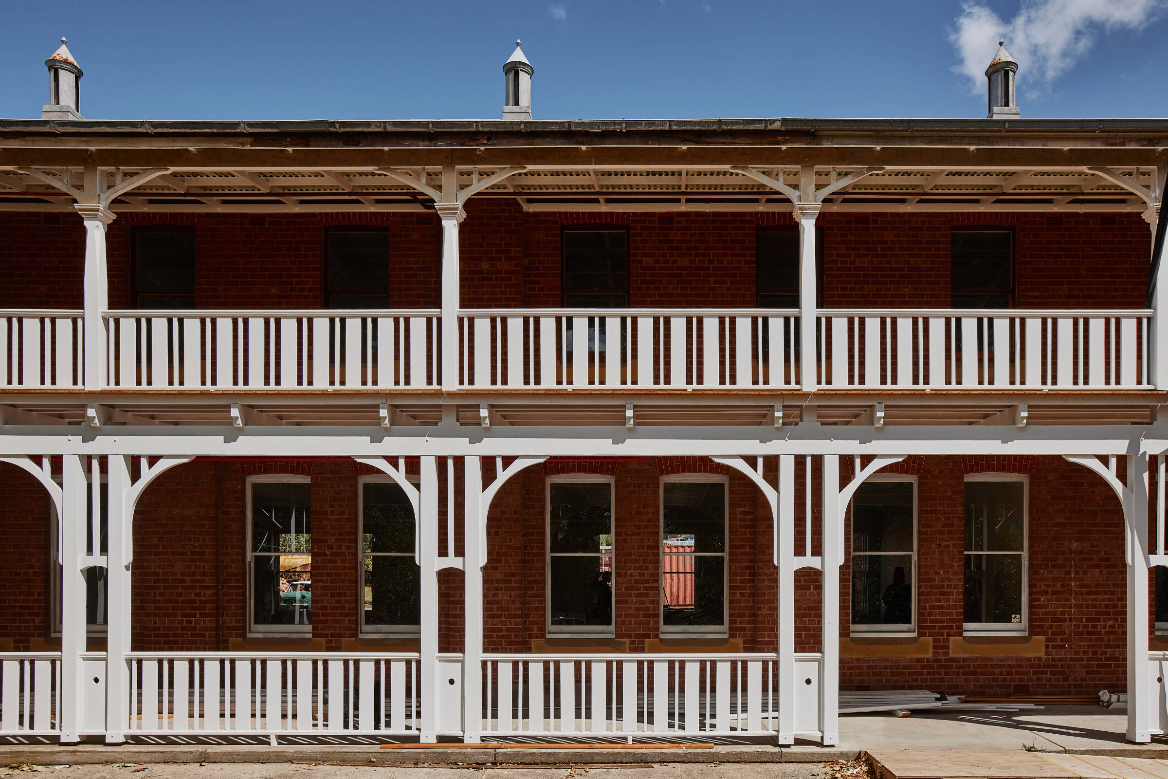 Front view of a double storey heritage building and a freshly painted white verandah with decorative supports and balustrades, and two heritage roof vents. Credit: Samuel Shelley.