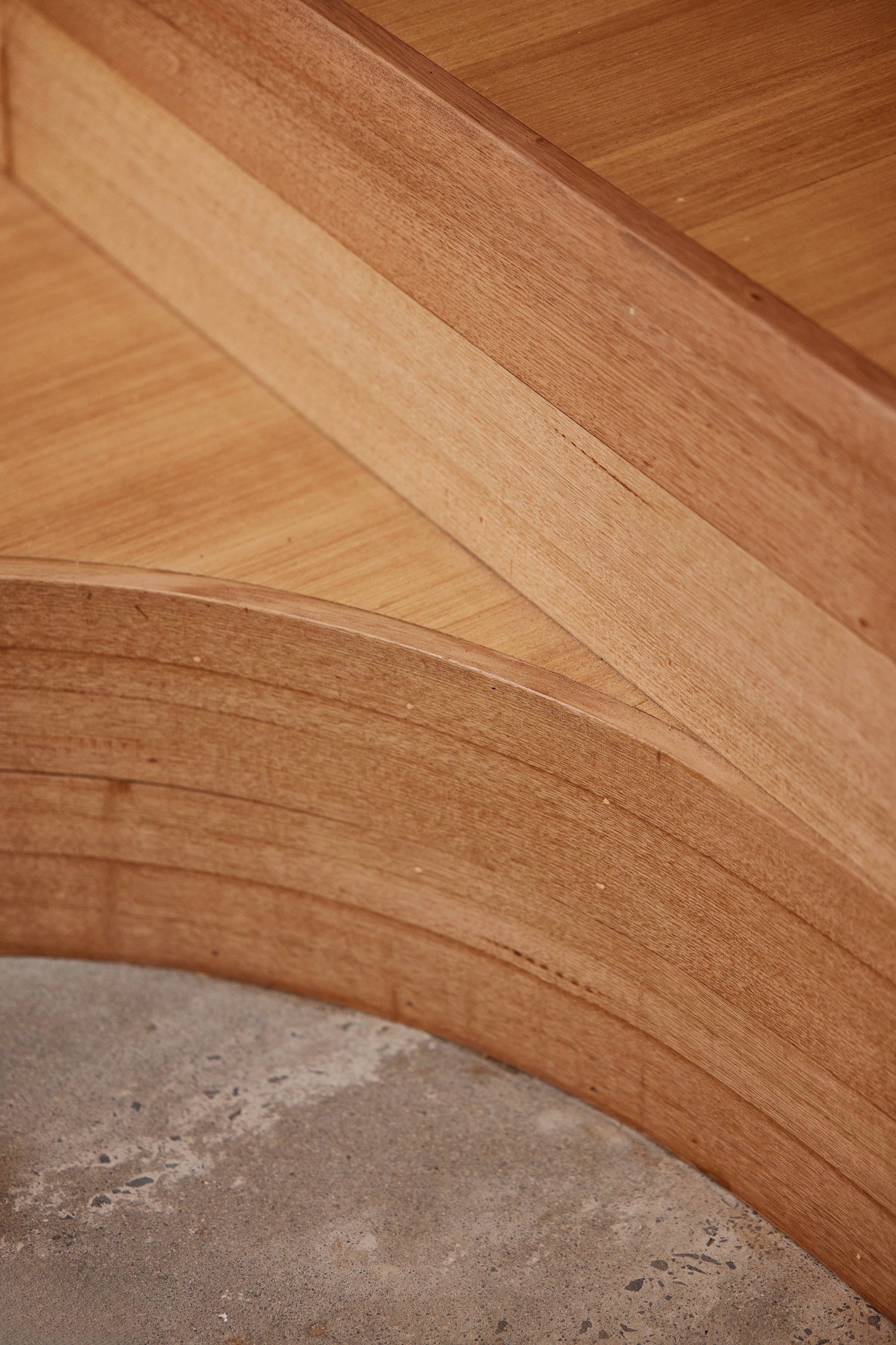 Closeup image of a curved Tasmanian oak board and other precisely laid flooring against a grey concrete floor. Credit: Samuel Shelley.