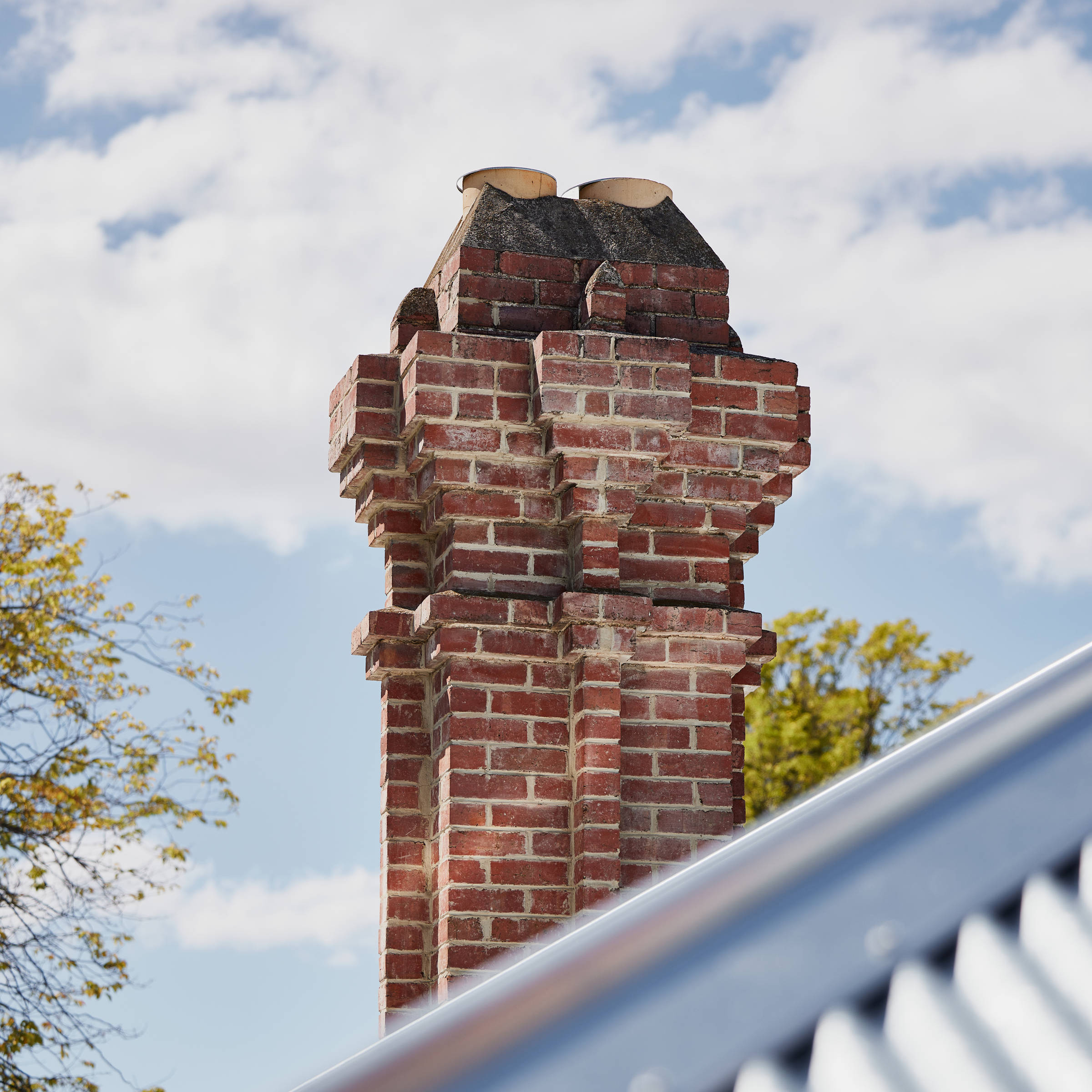 Multi-angled heritage chimney with internal chimney pots constructed from red brick and using white mortar as a feature. Credit: Samuel Shelley.