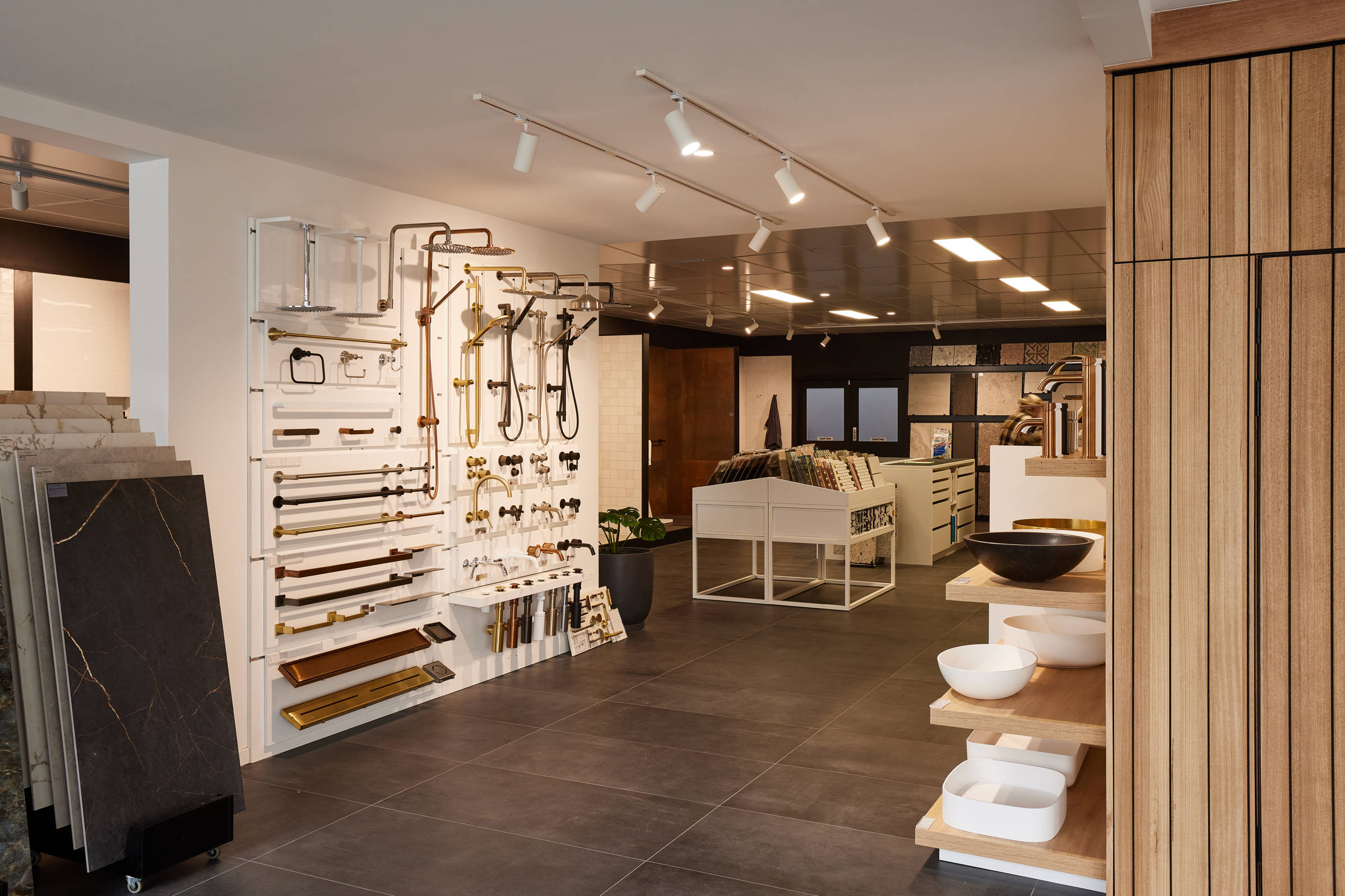 A large open showroom of a tile shop, featuring towel rails, shower heads, taps, basins and tile displays. Credit: Samuel Shelley.