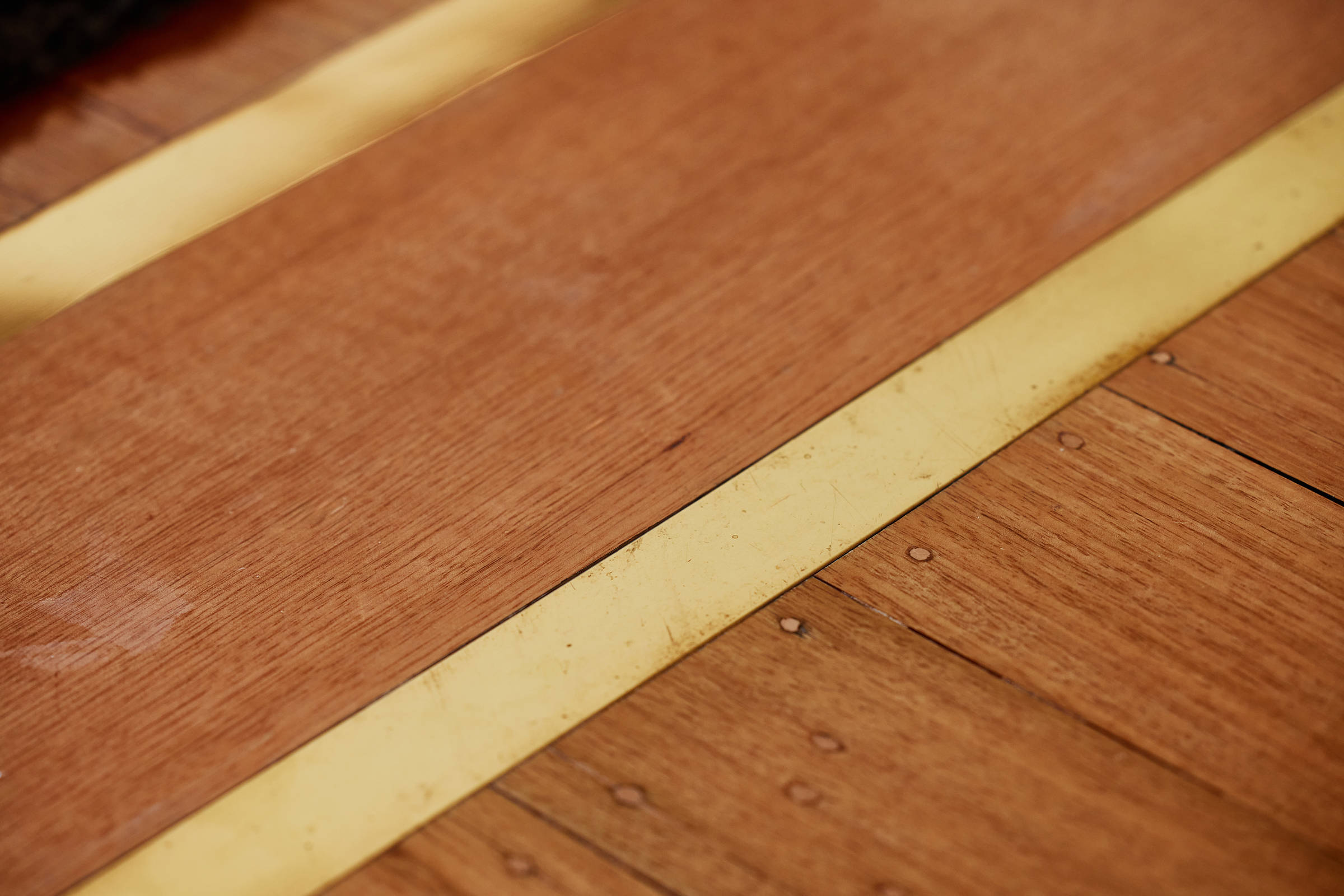 Detail of brass strips inlaid into a Tasmanian oak timber floor. Credit: Samuel Shelley.