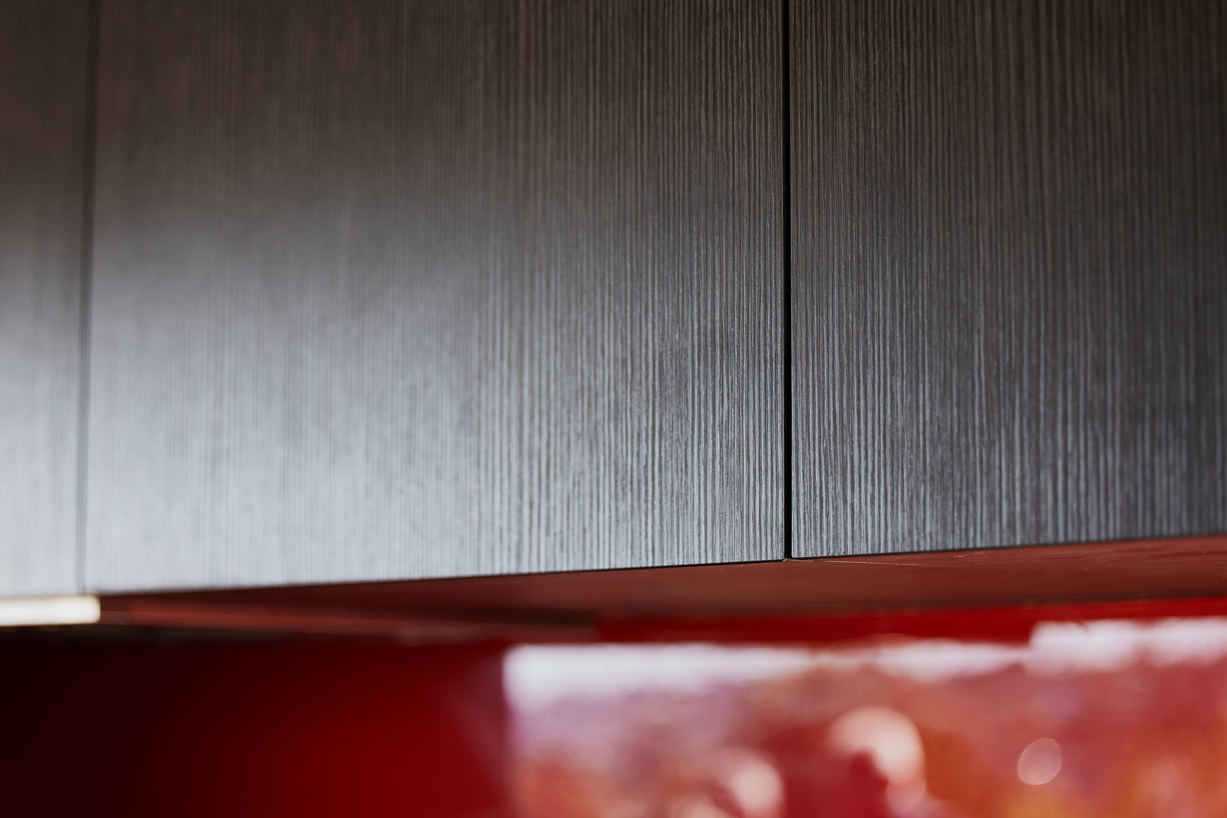 Closeup detail of the timber grain on the doors of the black kitchen cabinetry. Credit: Samuel Shelley.